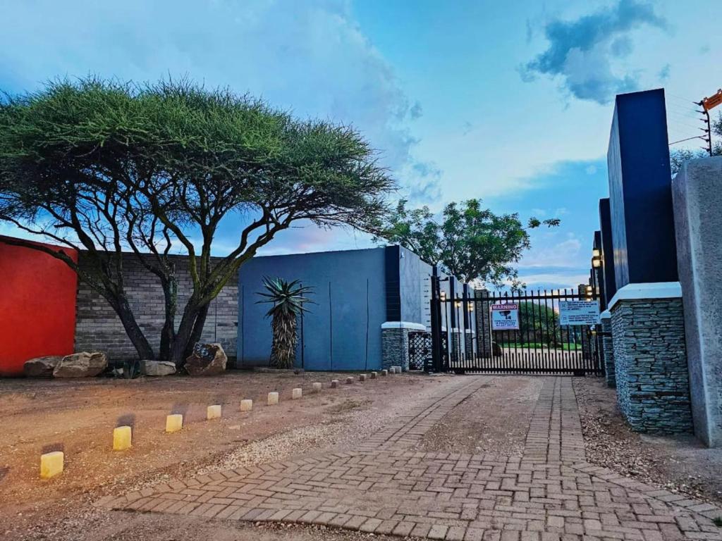 a gate with a tree in front of a building at Unique Overnight Polokwane Eco-Friendly & Solar Powered in Polokwane