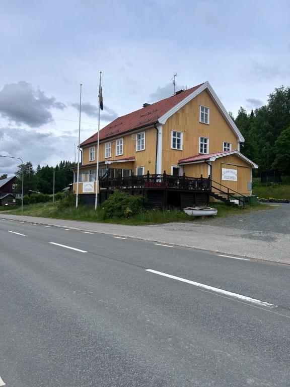 une grande maison jaune au bord d'une route dans l'établissement Gula Villan Värdshus, à Glommersträsk