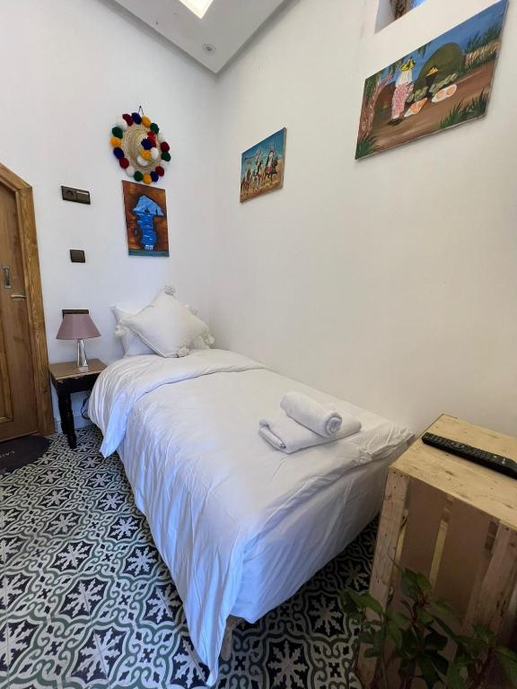 a bedroom with a large white bed and a table at Chambre au cœur de la médina avec salle de bain privé in Tangier