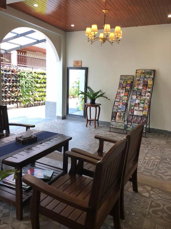 A lounge-like hotel lobby with wooden seating, a chandelier and an open garden-facing entrance.