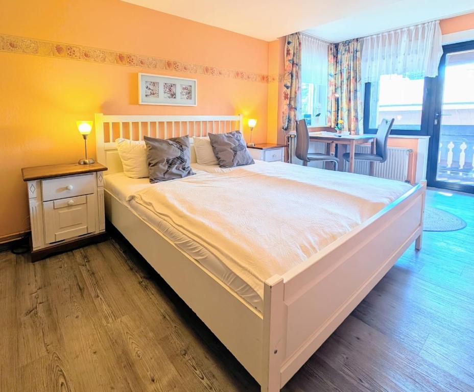 ein großes weißes Bett in einem Zimmer mit einem Tisch in der Unterkunft Haus Sabine - Zimmer 2 in Braunlage