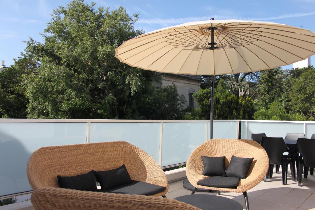 eine Terrasse mit 2 Stühlen und einem Sonnenschirm in der Unterkunft La Maison Blanche in Arles
