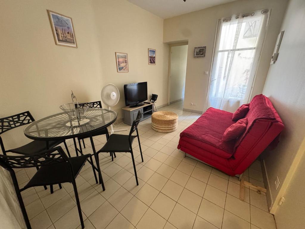 un salon avec un canapé rouge et une table dans l'établissement La loge d'Avignon, à Avignon
