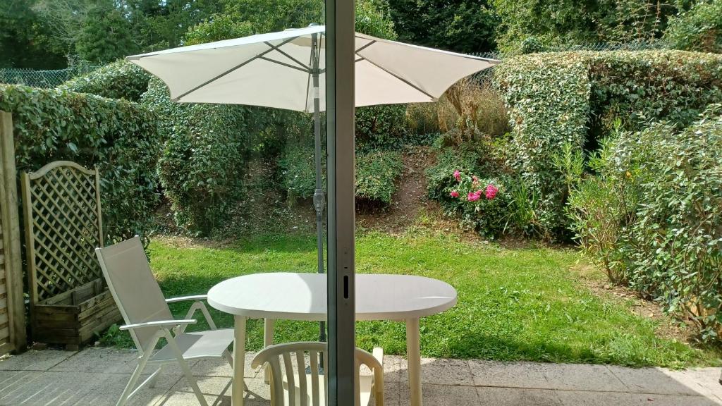 une table et une chaise blanches sous un parasol dans l'établissement STUDIO TERRASSE JARDIN VANNES, proximité port et centre historique, parking privé, à Vannes