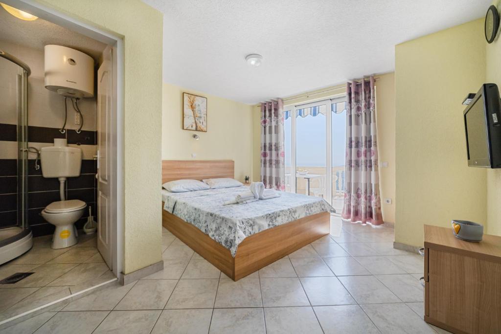 a bedroom with a bed and a toilet and a television at Apartments Dragičević 6 with Garage in Budva