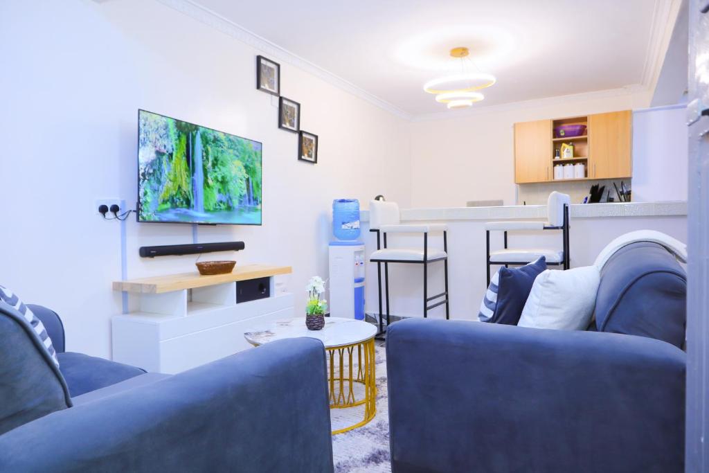 a living room with two blue couches and a tv at 1 bedroom in Kamakis in Ruiru