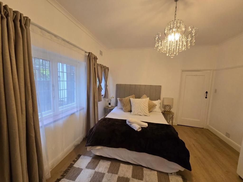 a bedroom with a large bed and a chandelier at Mead, Pinelands in Cape Town