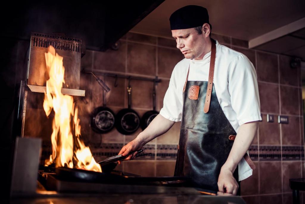 a man in a kitchen preparing food on a grill at Carlton George Hotel in Glasgow
