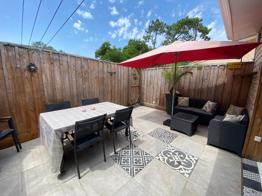 d'une terrasse avec une table et un parasol rouge. dans l'établissement Nid chaleureux proche de l'océan, à Lacanau