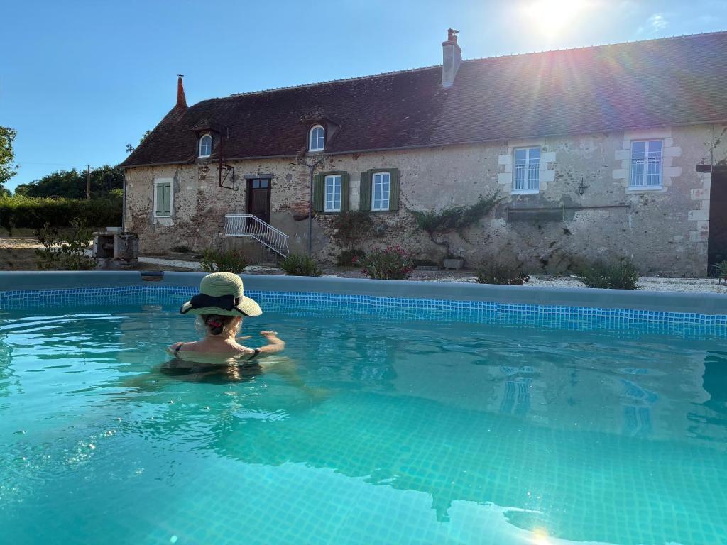a person in a hat in a swimming pool at Gîte de charme dans le Sancerrois in Bannay