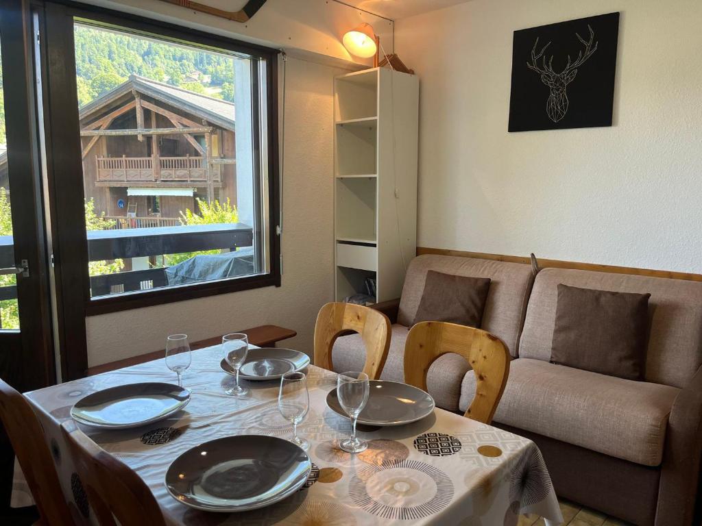 - une table à manger avec des chaises et un canapé dans l'établissement Chaleureux studio centre Samoëns, balcon, proche commodités et skibus - FR-1-624-83, à Samoëns