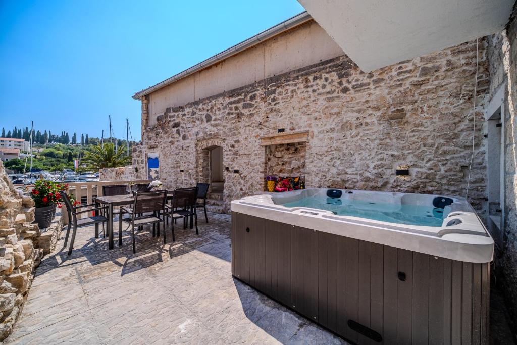 a hot tub on a patio with a table at Luxury Villa Unikat with Seaview & Jacuzzi in Milna