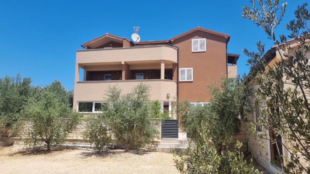 a house on the hill with trees in front of it at Lavanda Apartments in Pakoštane
