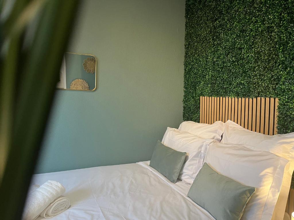 a bedroom with a bed with white sheets and pillows at Le Verdélite - Studio design & végétal proche gare et centre historique in Évreux