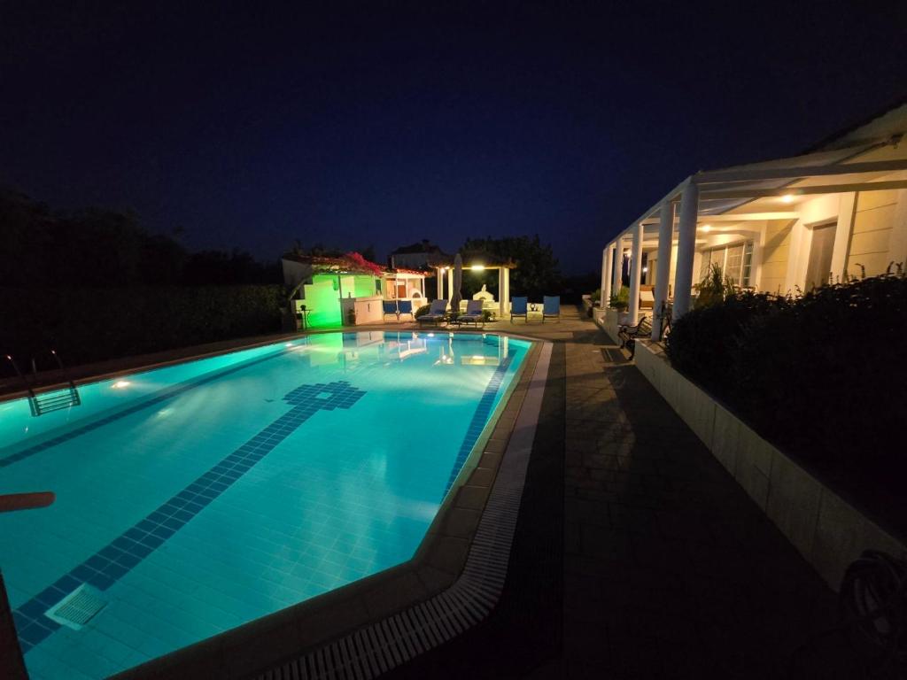 a swimming pool lit up at night at Elia Apartment Garden Oasis With Pool Astros in Paralio Astros