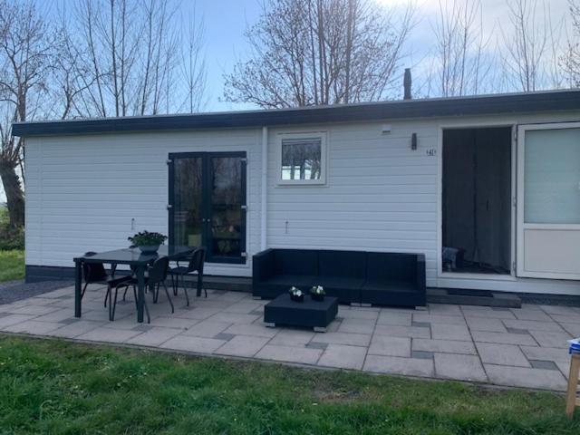 eine Terrasse mit Tisch und Stühlen vor einem Haus in der Unterkunft Landelijk gelegen chalet aan de Vecht vlakbij Amsterdam in Nigtevecht