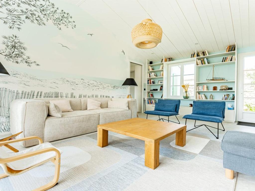 ein Wohnzimmer mit einem Sofa und blauen Stühlen in der Unterkunft Maison de vacances avec jardin verdoyant à Loix - FR-1-835-25 in Loix