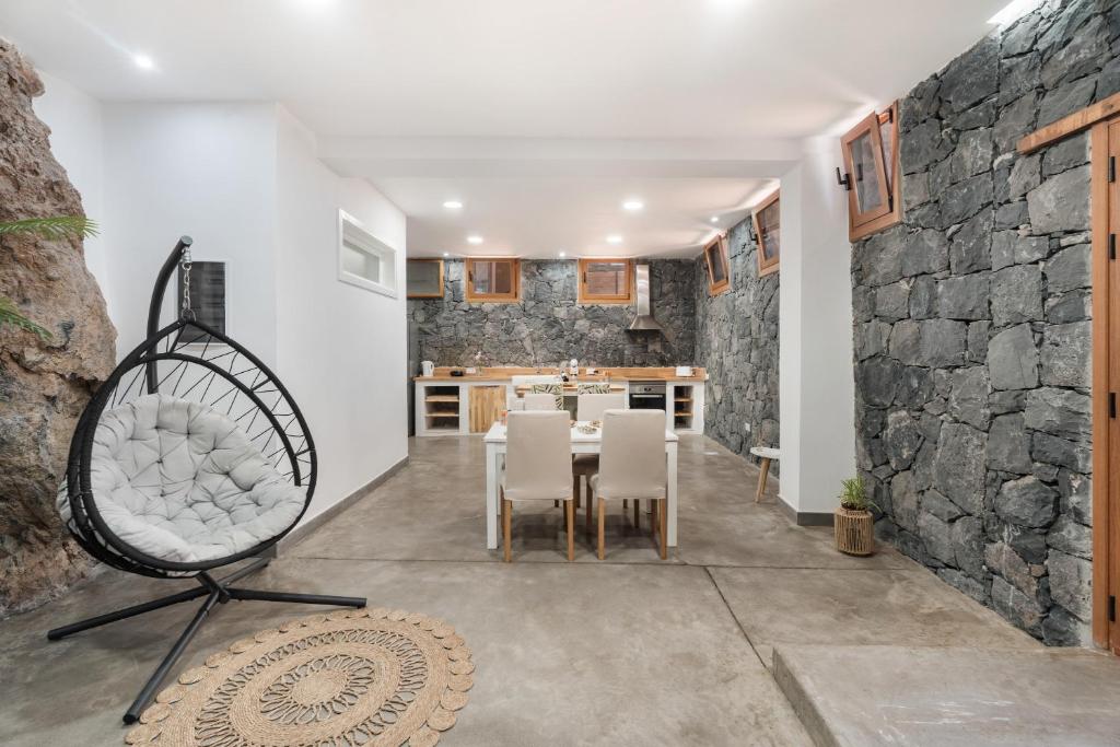 una cucina e una sala da pranzo con parete in pietra di Luxury Home la Cueva del Guanche ad Adeje