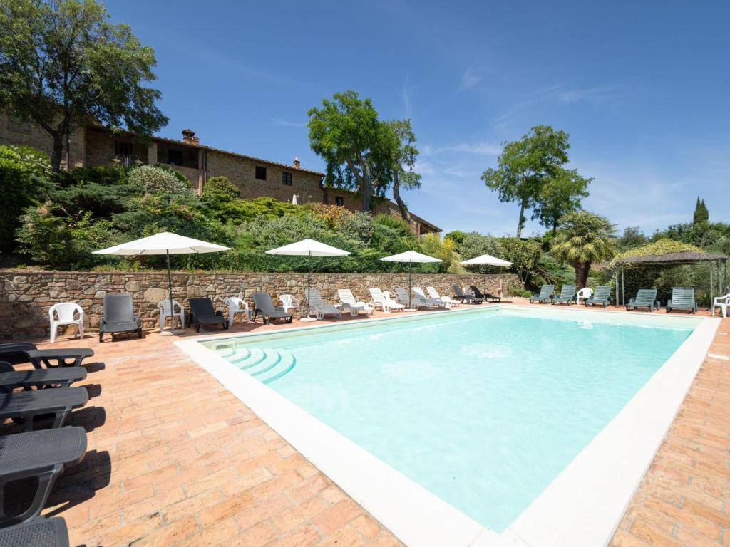 a swimming pool with chairs and umbrellas at Apartment Raffaello by Interhome in Montaione