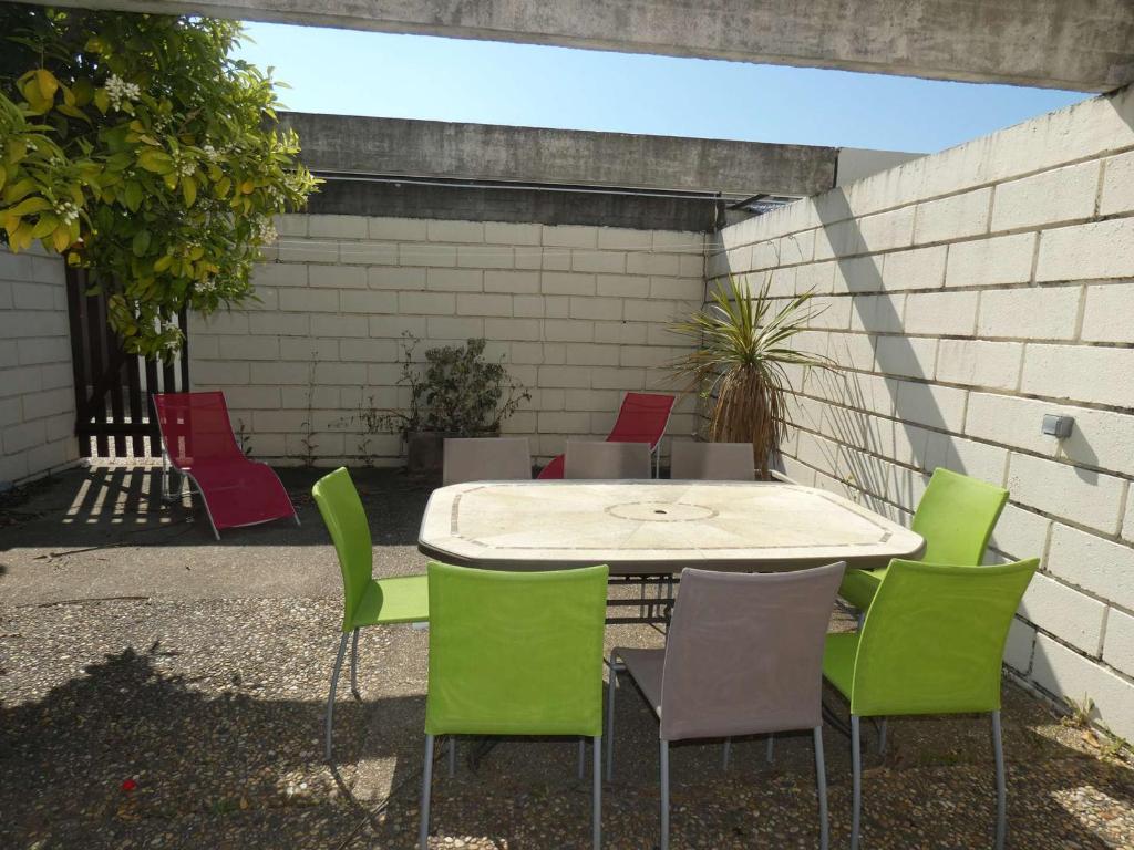 une table et des chaises dans une terrasse avec un mur dans l'établissement Villa Rénovée en Duplex, 8 Pers, 3 Ch, Patio, Clim, Proche Plage et Centre - La Grande-Motte - FR-1-328-109, à La Grande Motte