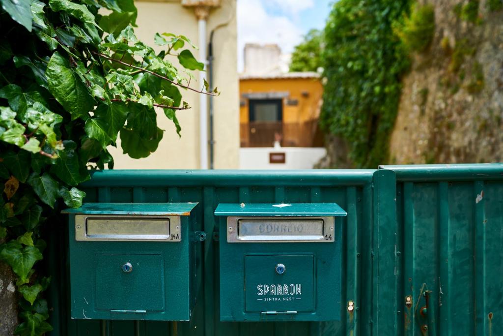 two mailboxes sitting next to a green fence at Sparrow Sintra Nest in Sintra