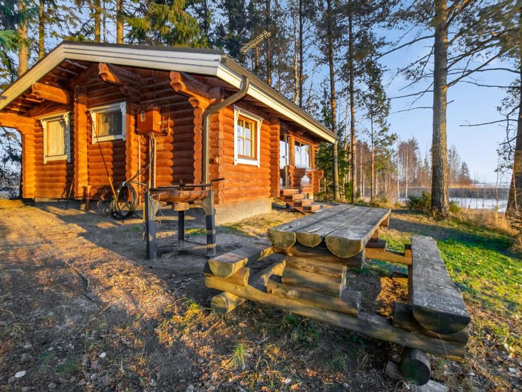 una cabaña en el bosque con un banco y una mesa en Holiday Home Huvilakoti 2 by Interhome, en Puromäki