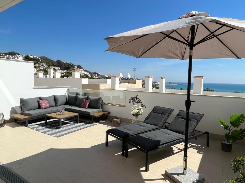 un patio con 2 sofás y una sombrilla en Lovely New Luxery Beach Apartment in Mojacar Playa next to the best beach, en Mojácar