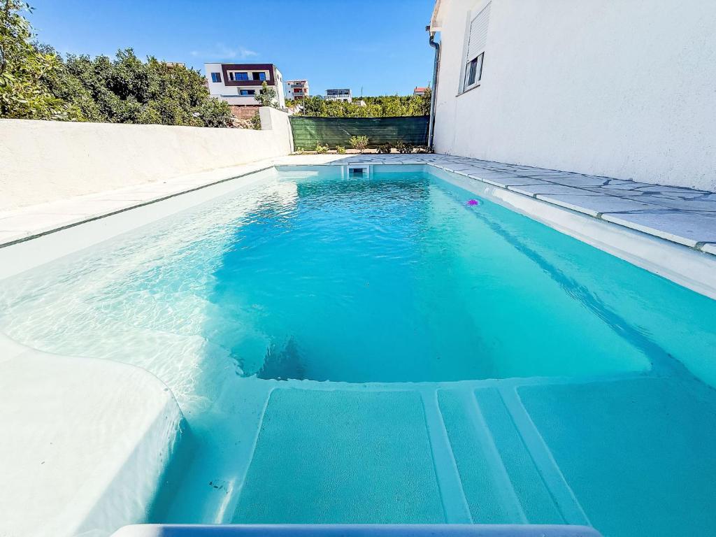 a pool of blue water next to a building at Holiday Home Dalmatina by Interhome in Maslenica