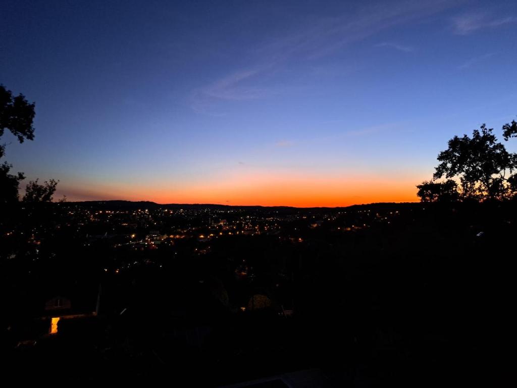 a sunset view of a city with a tree at Brive, La Villa Bellevue in Buissou