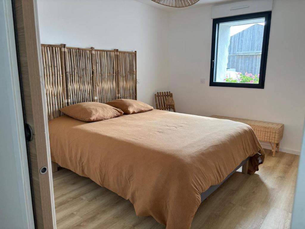 a bedroom with a bed with a wooden headboard and a window at Gîte des capucines in Plougonvelin
