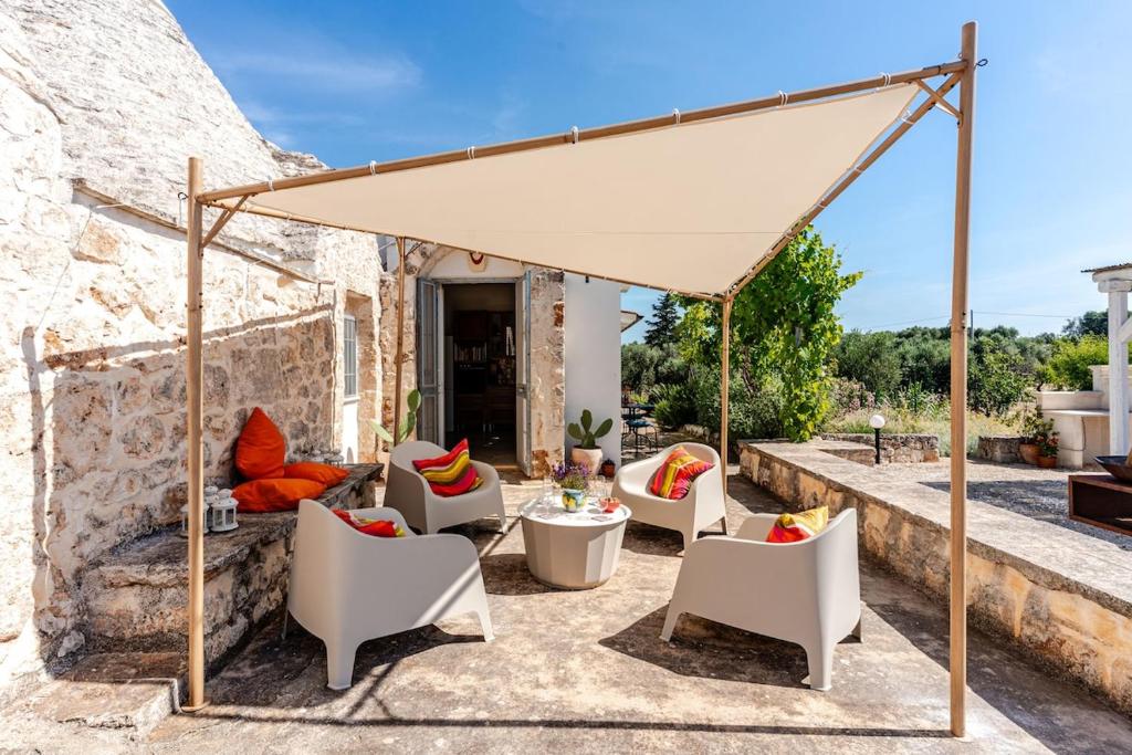 ein weißes Vordach auf einer Terrasse mit Stühlen und Tischen in der Unterkunft Casa Sordella in San Michele Salentino
