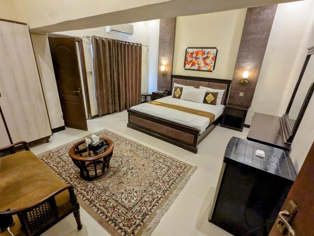 a bedroom with a bed and a couch and a table at shelton guest House in Lahore