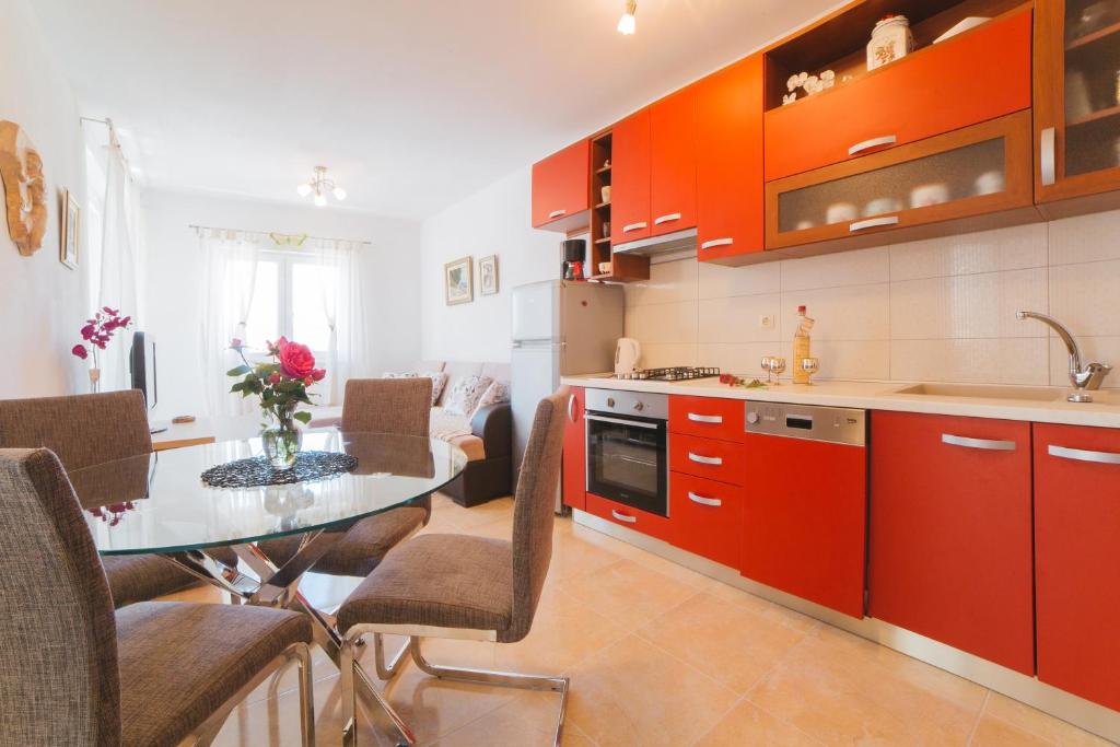 une cuisine avec des armoires orange et une table avec des chaises dans l'établissement Apartments Miamare, à Seget Vranjica