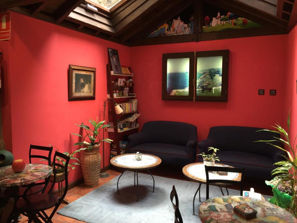 a living room with red walls and a couch and tables at La Posada del Rey in Llanes