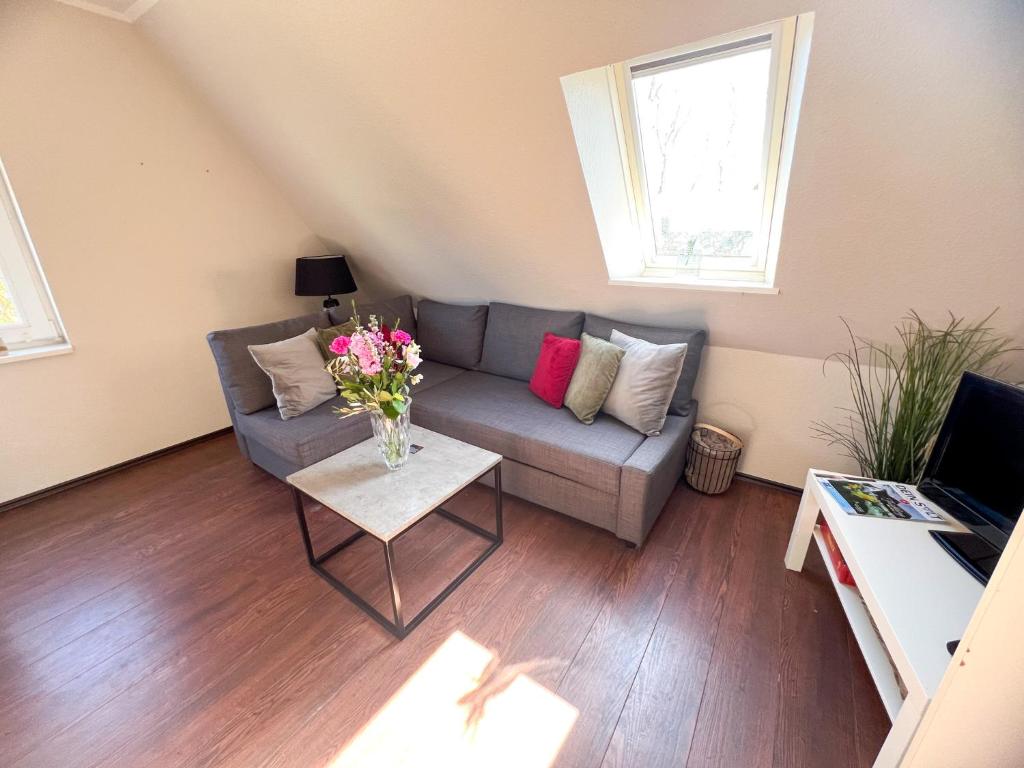 a living room with a couch and a table with flowers at Exclusives Apartment im Herzen von Westerland in Westerland (Sylt)