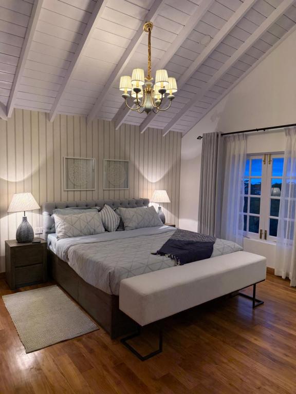 a large bedroom with a large bed and a chandelier at Villa Dhūmragiri in Maskeliya