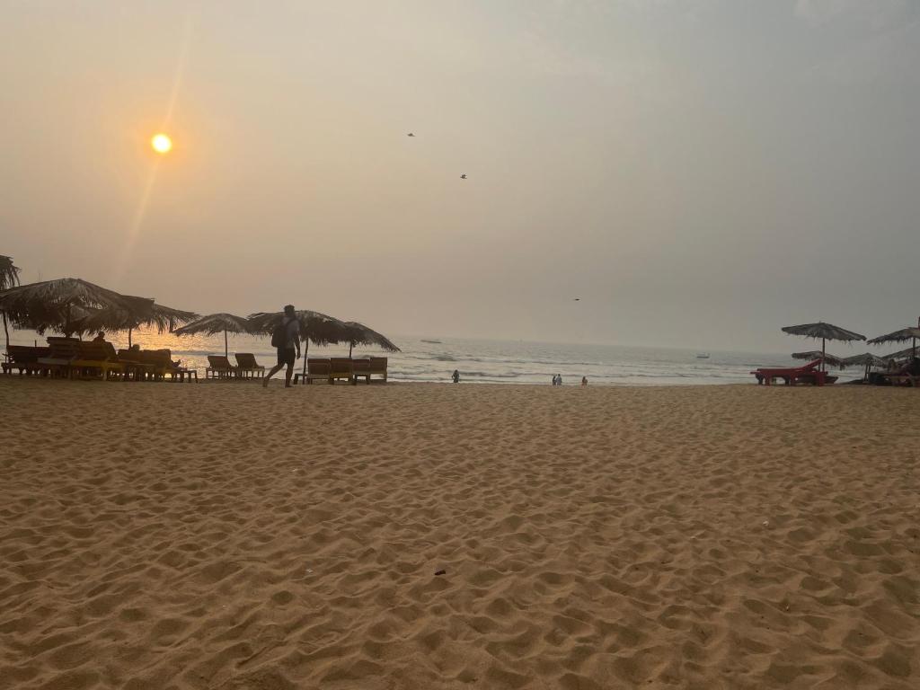 a person walking on a sandy beach with umbrellas at Richita resort in Calangute