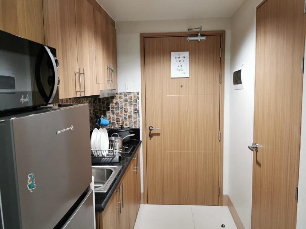 a kitchen with a refrigerator and a sink and a door at Mall of Asia Staycation shore 3 in Manila
