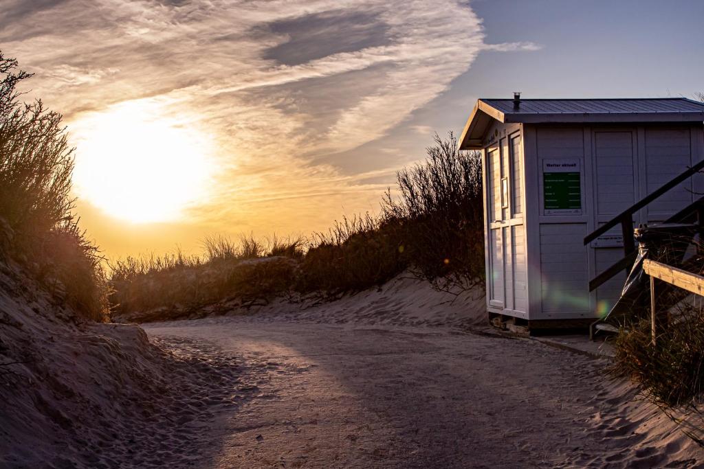 a small shack on a dirt road with the sunset at Kuscheliges Sylt Zuhause für 2 Personen in Westerland (Sylt)
