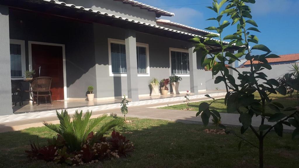 a white house with a porch and a yard at Vila Sunset Saquarema RJ in Saquarema