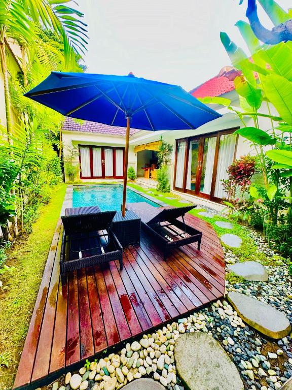 a wooden deck with a blue umbrella and benches at Villa LAKSMI in Seminyak