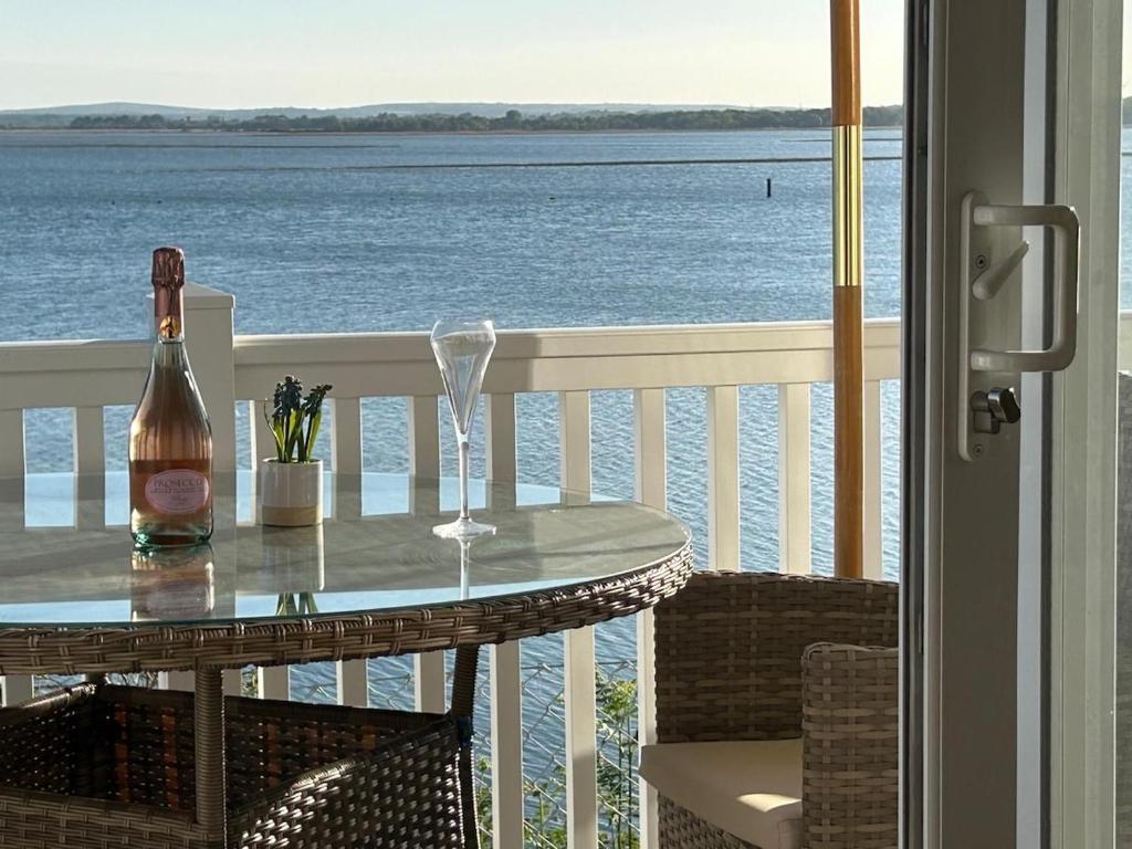 a table with a bottle and a wine glass on a balcony at Unobstructed Sea Views , Rockley Park , Poole in Lytchett Minster