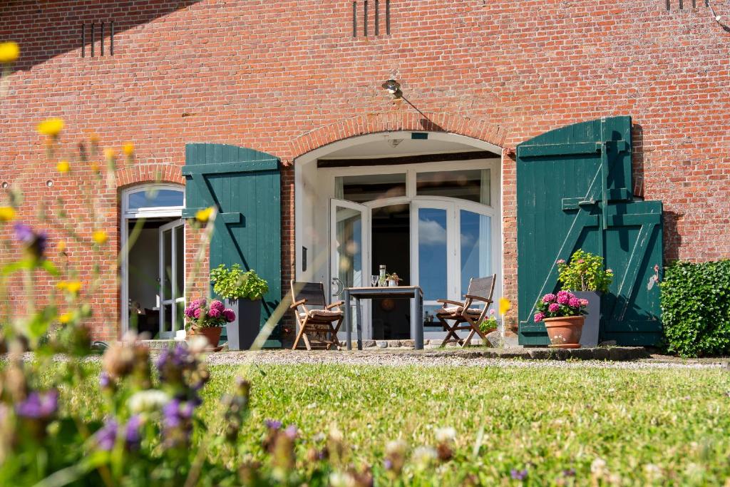 a brick building with green doors and a patio at Fewo - Landblick in Roge