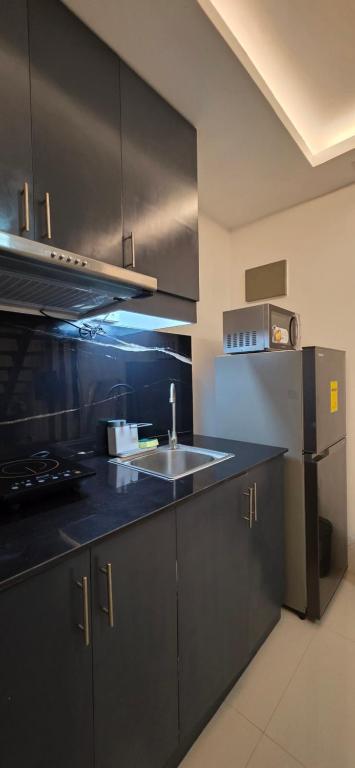 a kitchen with black cabinets and a sink at 2BR Bi-Level BGC Skyline 150mbps WiFi in Sampong