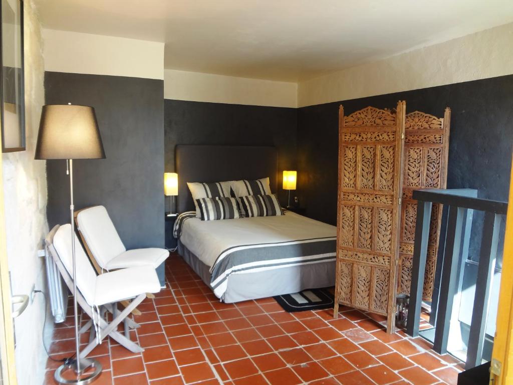 a bedroom with a bed and a chair and a door at Les toîts d&#39;Uzès in Uzès