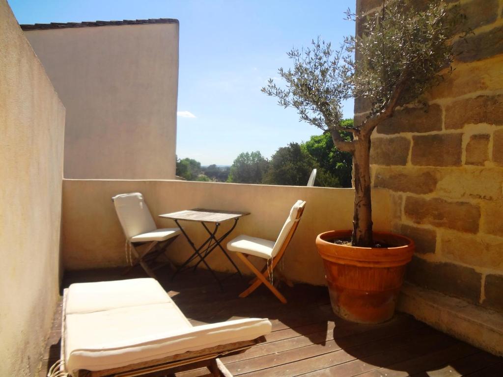 a balcony with a table and chairs and a tree at Les toîts d&#39;Uzès in Uzès