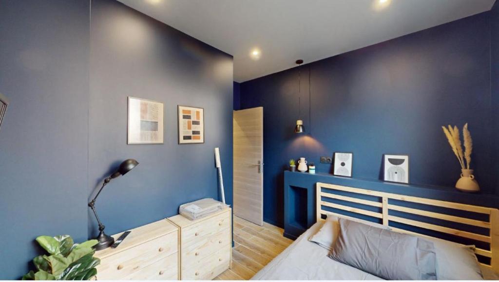 a bedroom with a blue wall with a bed and a dresser at Jupiter Paris in Champigny-sur-Marne