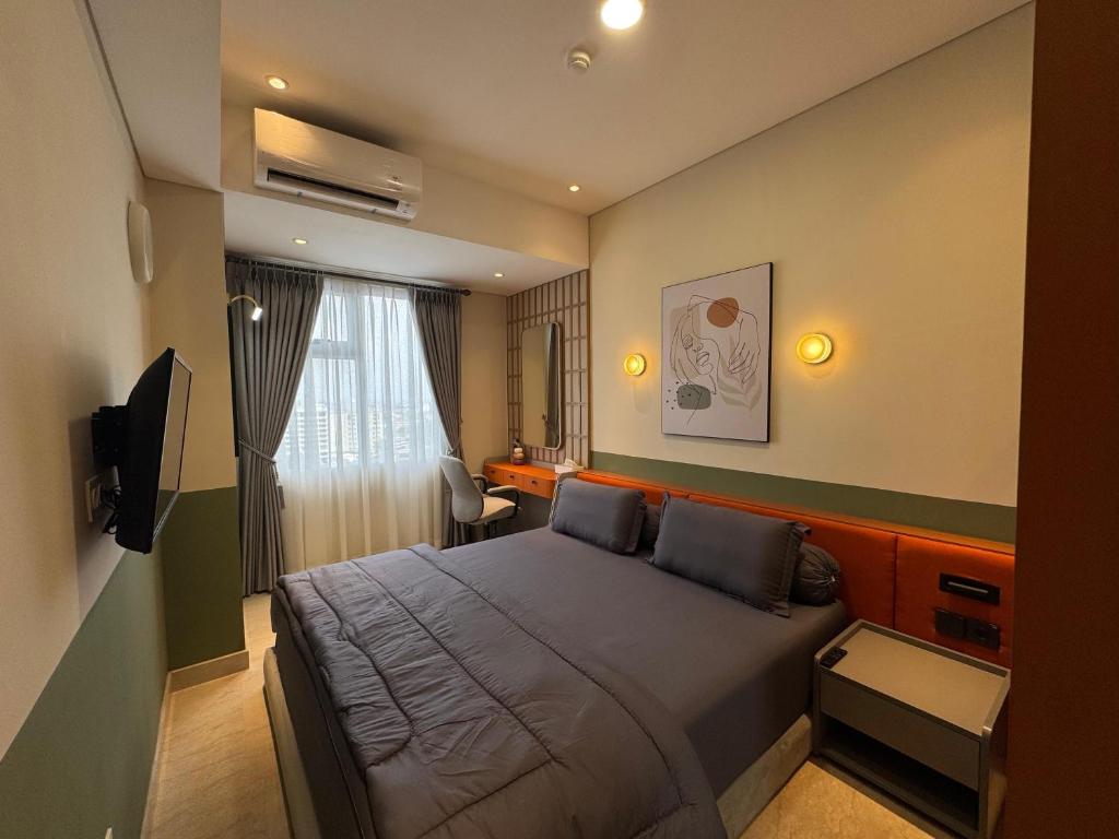 a bedroom with a large bed and a television at Podomoro Medan Lexington Tower - Japandi Modern - New Renovated 2 BR- direct mall access in Medan