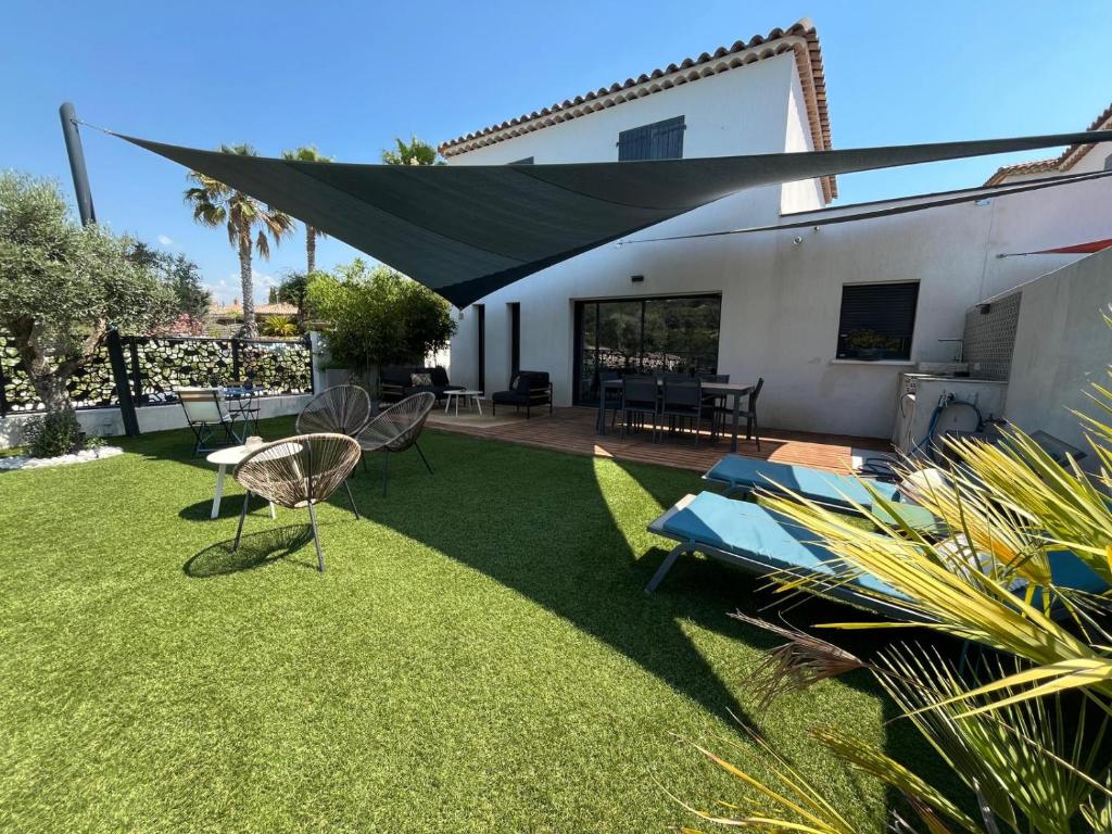 un patio avec un auvent noir sur une pelouse dans l'établissement Le Castellet Maison de vacances, au Castellet