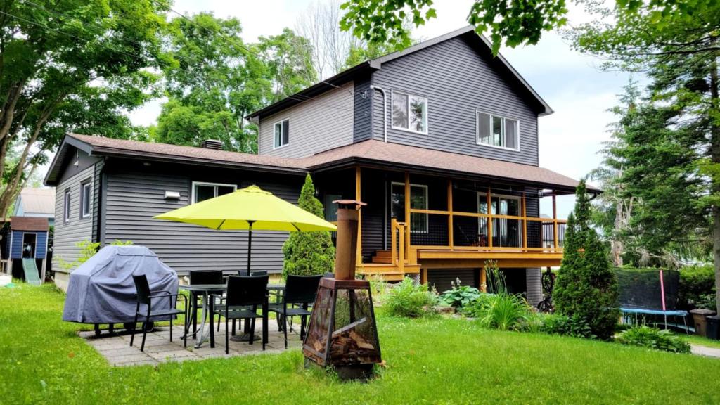 une maison avec une table, des chaises et un parasol jaune dans l'établissement Chalet Ô Lac-Brome, 3ch, 8 personnes, à Lac-Brome